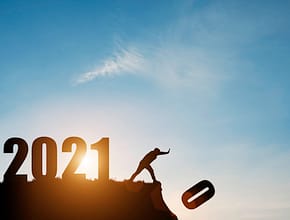 Man push number zero down the cliff where has the number 2021 with blue sky and sunrise. It is symbol of starting and welcome happy new year 2021.