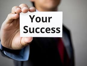 Businessman presenting 'Your Success' word on white card.