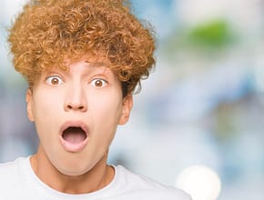 Young man holding a soccer ball with a very surprised face.