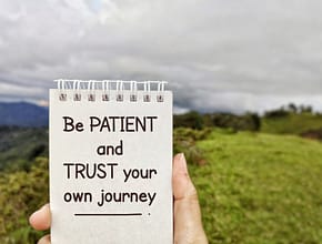 Be patient and trust your own journey. Text written on notepad background.